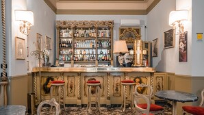 Un espace bar doté d’une décoration raffinée, d’une grande variété de bouteilles d’alcool et de sièges avec des coussins rouges.