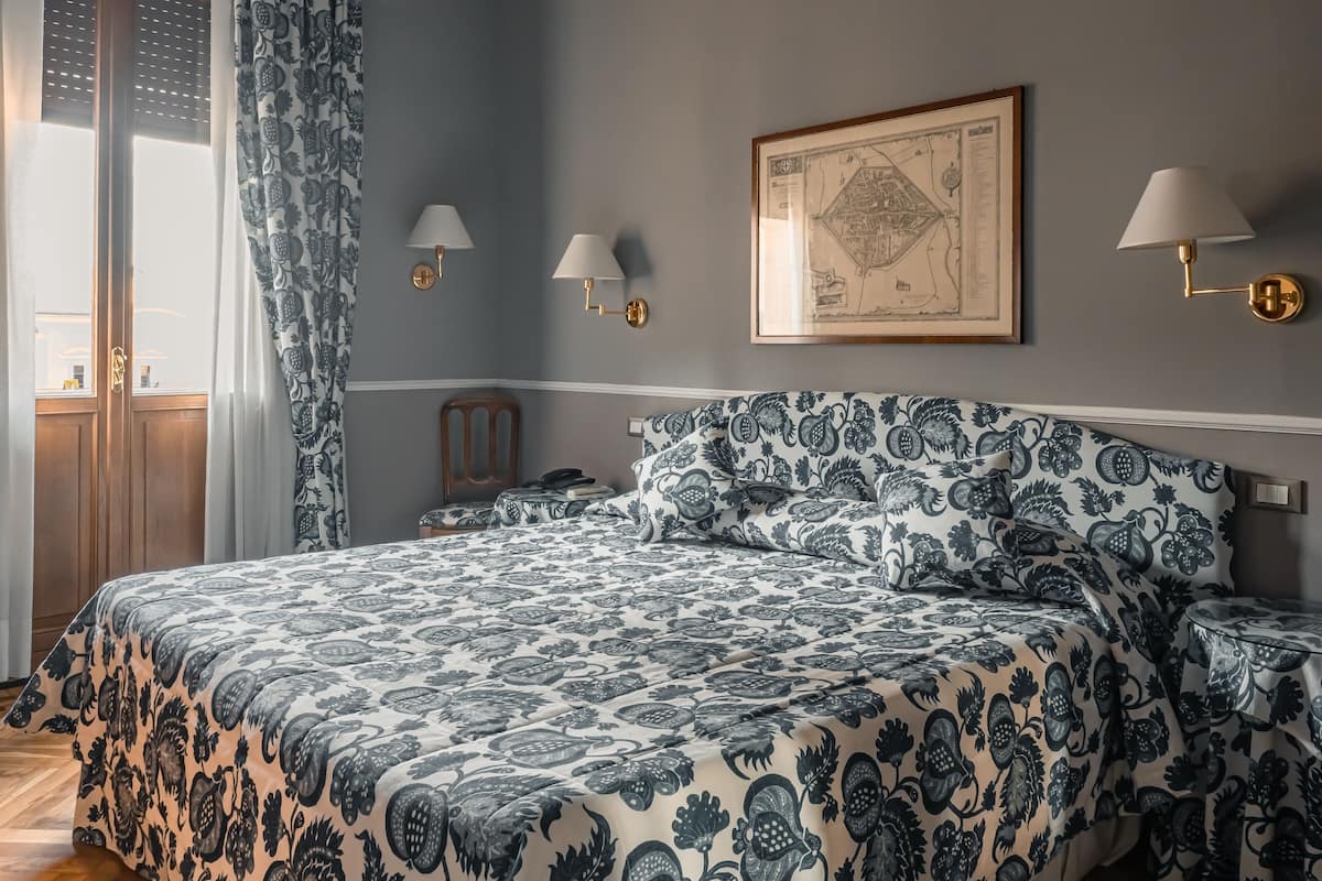 Un dormitorio con una cama grande, dos lámparas de noche, un mapa enmarcado en la pared y una mesita de noche de madera.