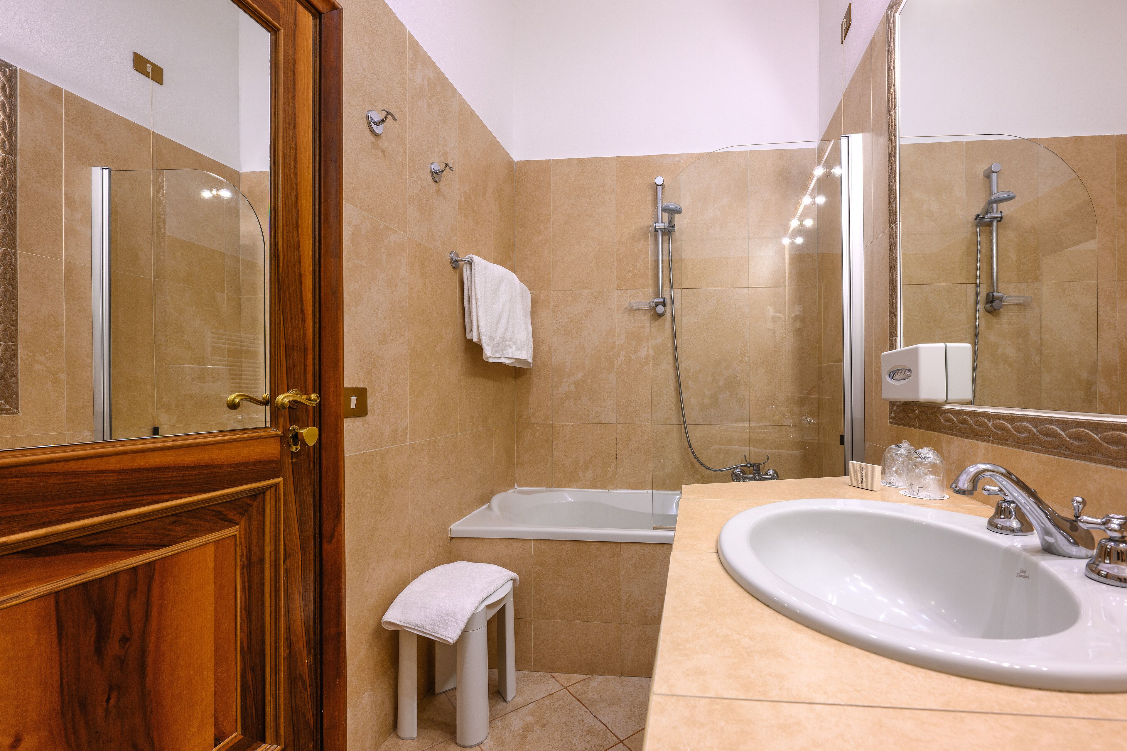 A bathroom with a wooden door, a white sink, a bathtub, and a shower.