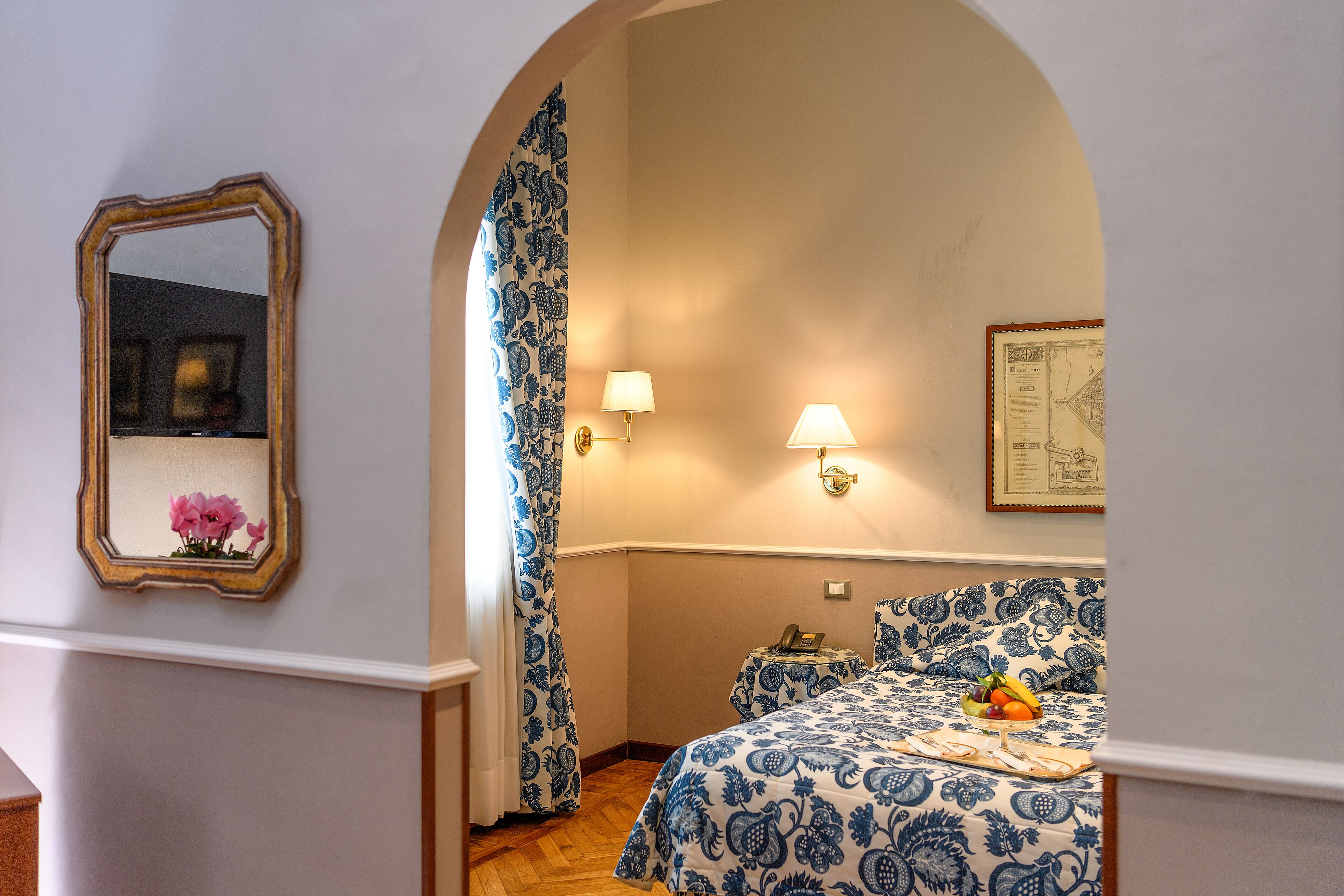 Una camera da letto con un letto, un comodino, una lampada, uno specchio e un quadro appeso al muro.