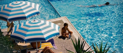 Una piscina al aire libre de temporada, sombrillas