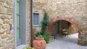 A stone building with a small courtyard, a window, and a door.