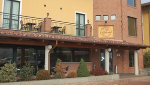 A hotel with a yellow facade, a brick tower, and a balcony with outdoor seating. - Hotel Villa Glicini (San Secondo di Pinerolo)