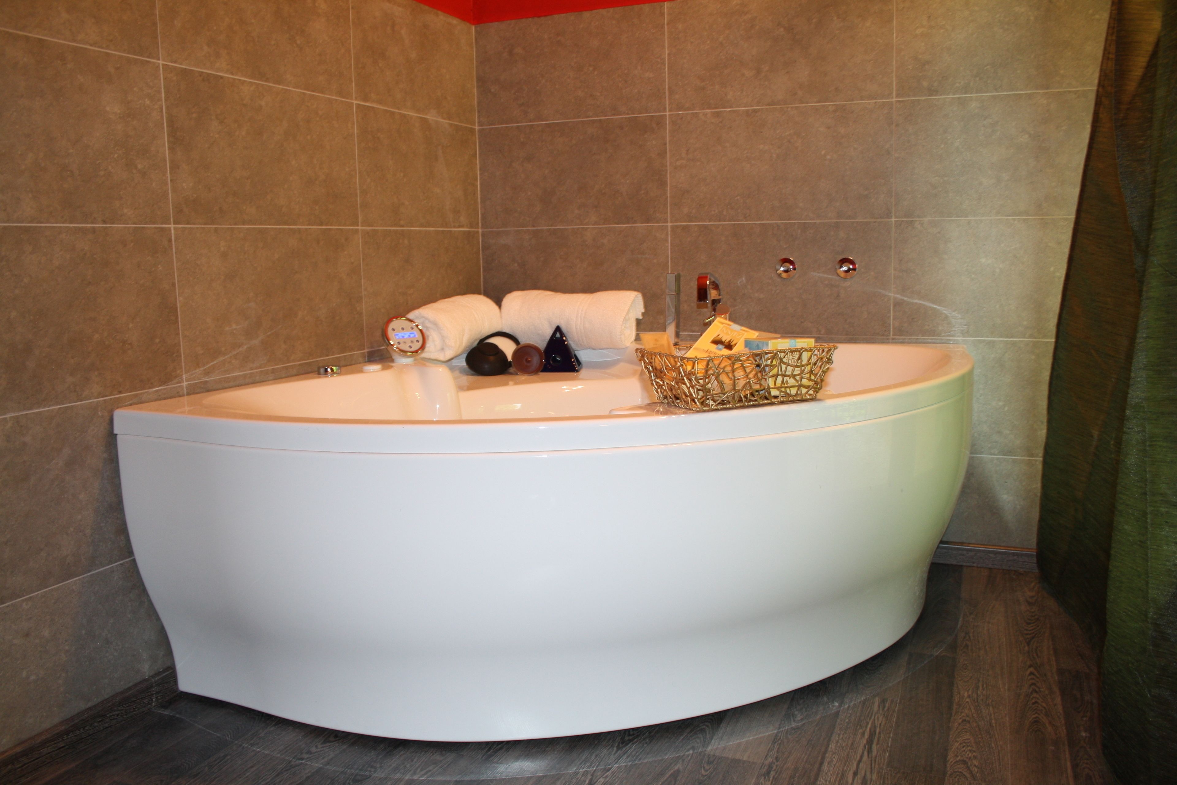 Une grande baignoire blanche au design incurvé, entourée de carreaux bruns.