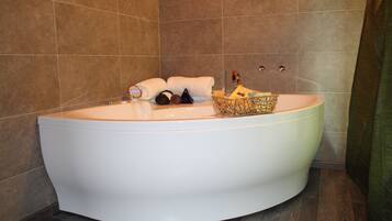 Une grande baignoire blanche au design incurvé, entourée de carreaux bruns.