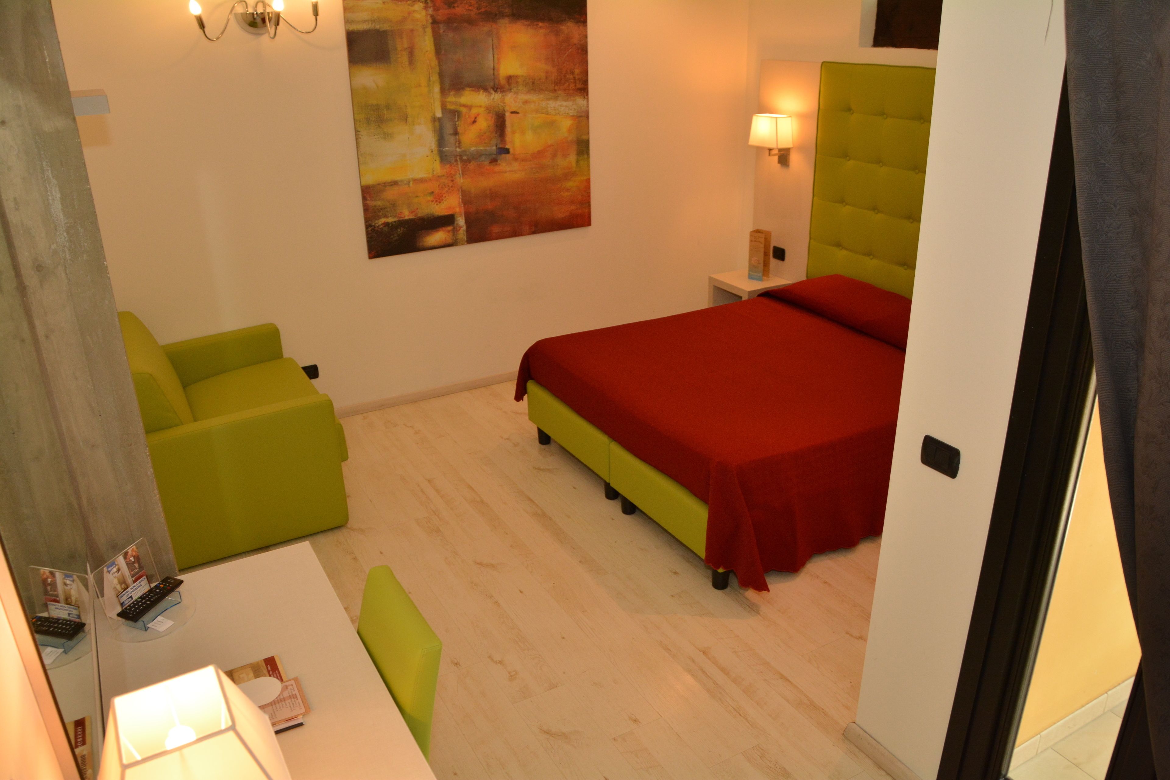 Una habitación de hotel con una cama, un sillón verde y un cuadro en la pared.