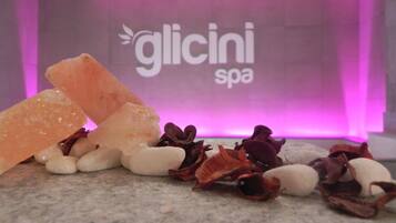 A spa setting with a sign reading "glicini spa" and various stones and crystals on a marble surface.