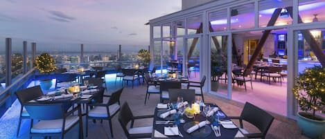 Un restaurante en la azotea con mesas dispuestas para comer, con vistas a la ciudad.