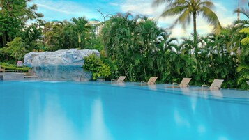 Una piscina al aire libre, sombrillas, sillones reclinables de piscina