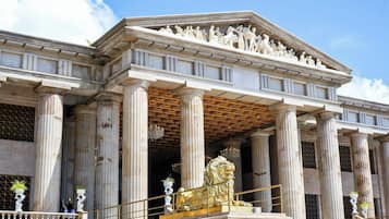 A classical building with columns, a central entrance, and a detailed sculpture above the doorway.
