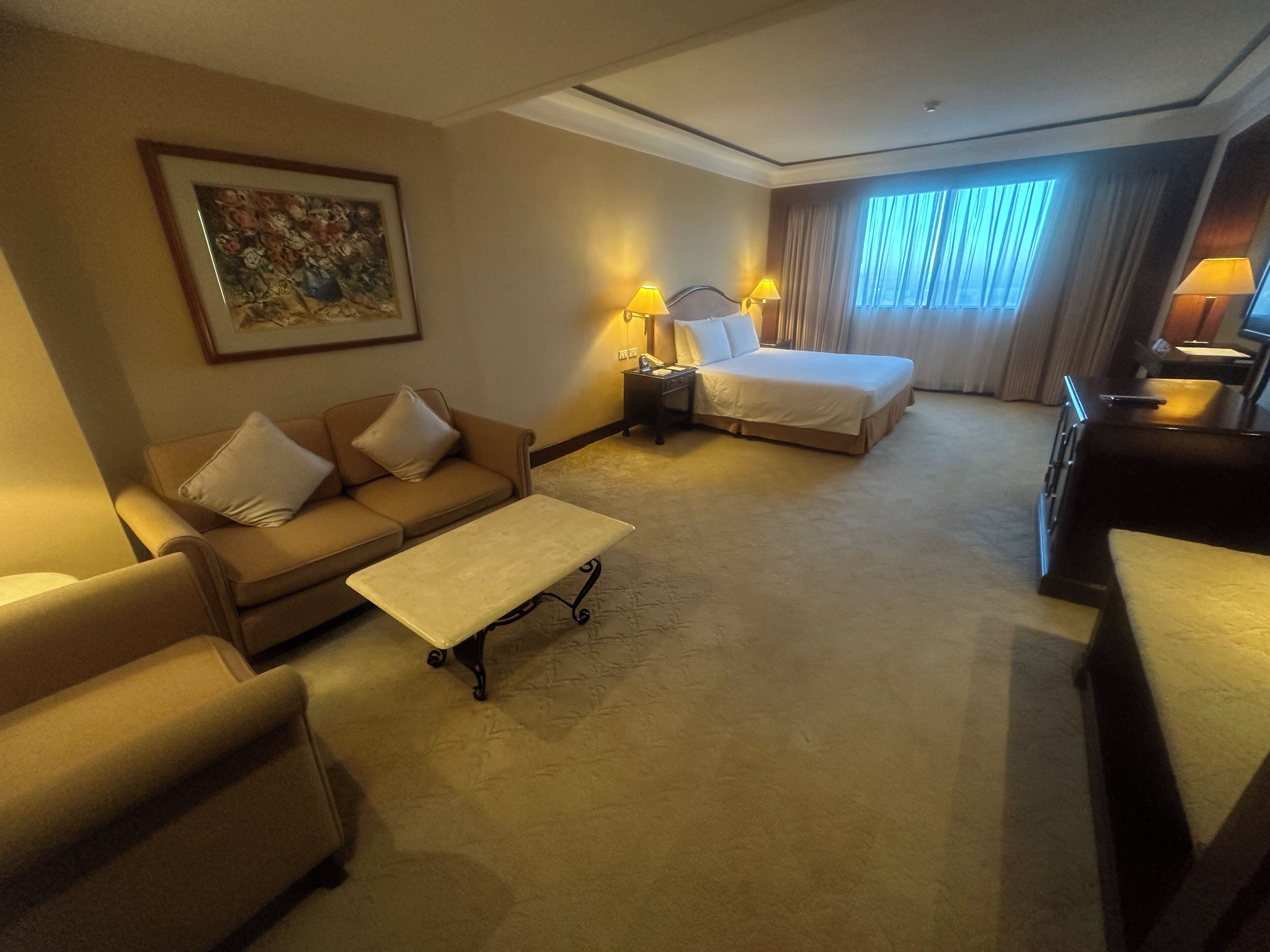 Une chambre d’hôtel avec un lit, un canapé, une table basse et un bureau.