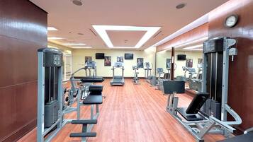 A gym with treadmills, weight machines, and a mirror wall.