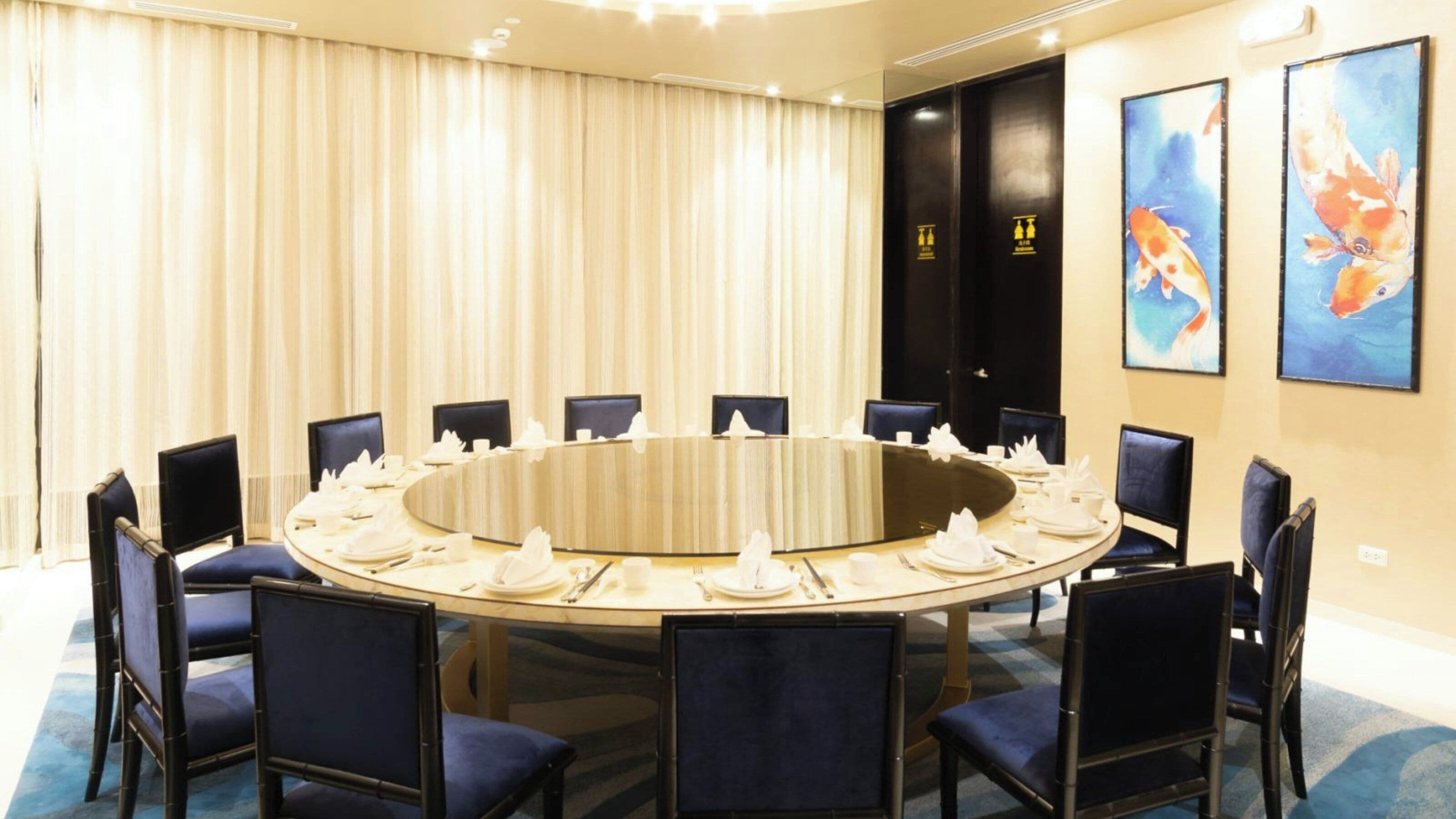 A conference room with a round table, chairs, and a buffet setup.