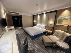 A hotel room with a large bed, a desk with a chair, a small table, and a sofa. - Marco Polo Plaza Cebu (Cebu City)