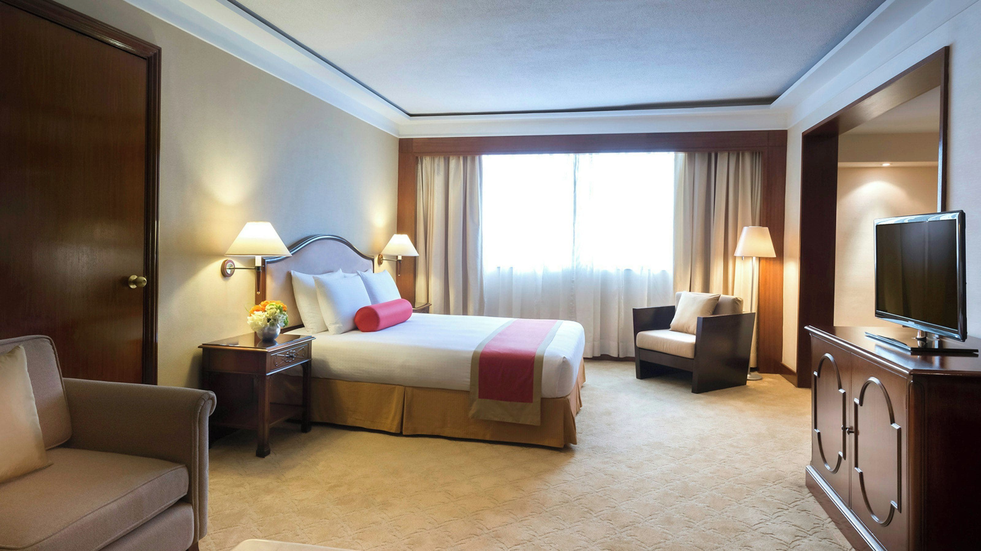 A hotel room with a bed, a TV, a desk, and a chair.