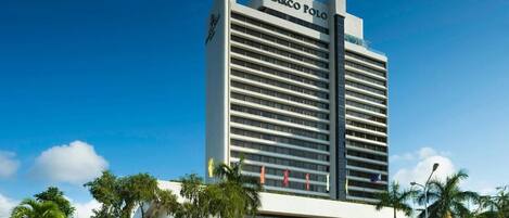 A tall hotel building with 'Marco Polo' signage, featuring a modern architectural design with horizontal lines and a flat roof.