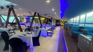 A restaurant with tables and chairs, a bar area, and a view through large windows. - Marco Polo Plaza Cebu (Cebu City)
