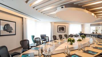 A modern conference room with a long table, chairs, water bottles, and framed artwork on the walls.