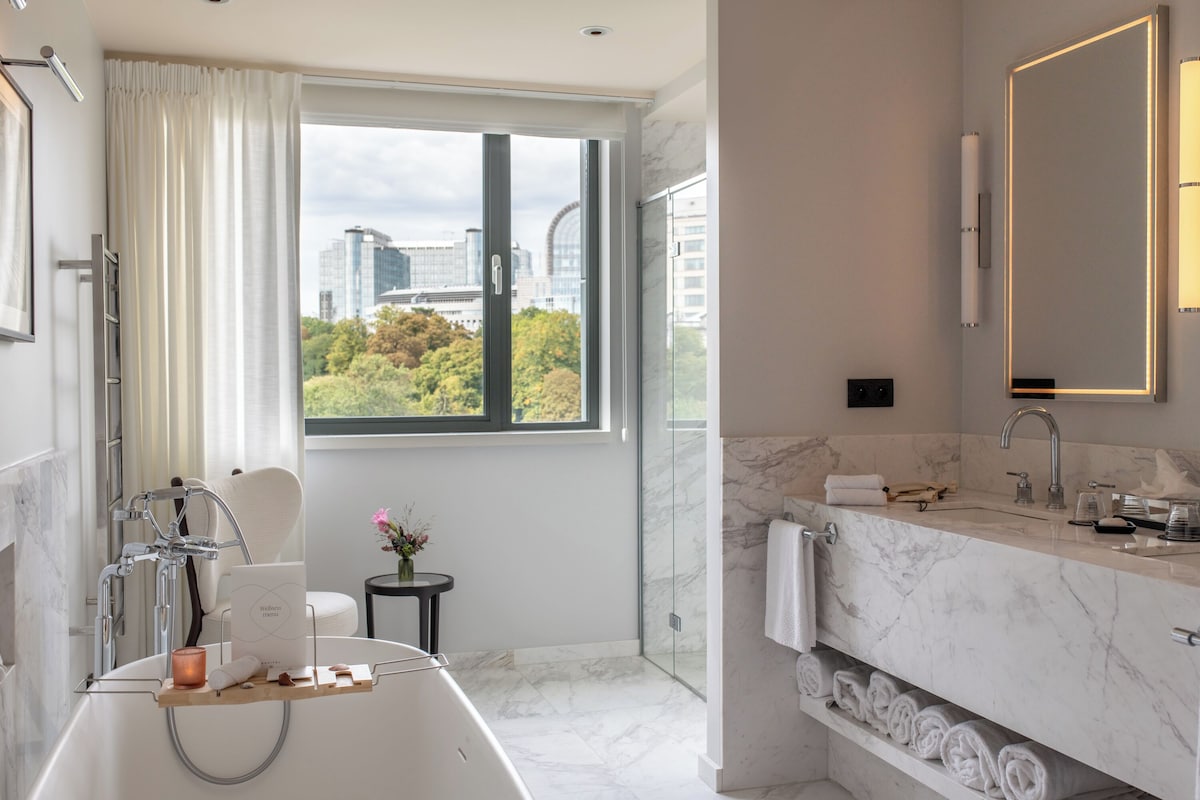 A modern bathroom with a large bathtub, a glass-enclosed shower, and a marble countertop.