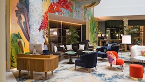 A spacious lobby with a central staircase, multiple seating areas, and a large mural. - Sofitel Brussels Europe (Brussels)