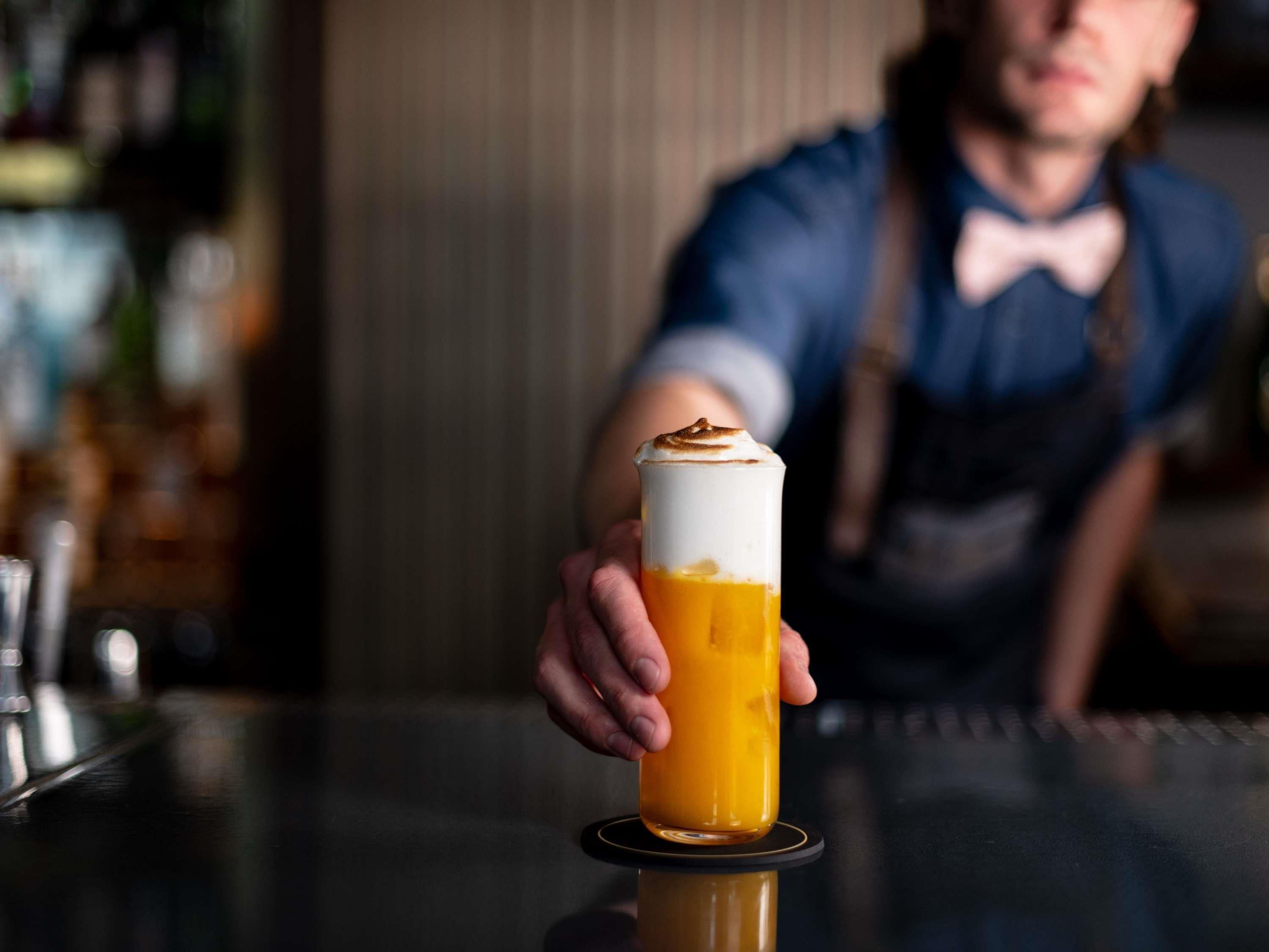 A bar setting with a person serving a drink.