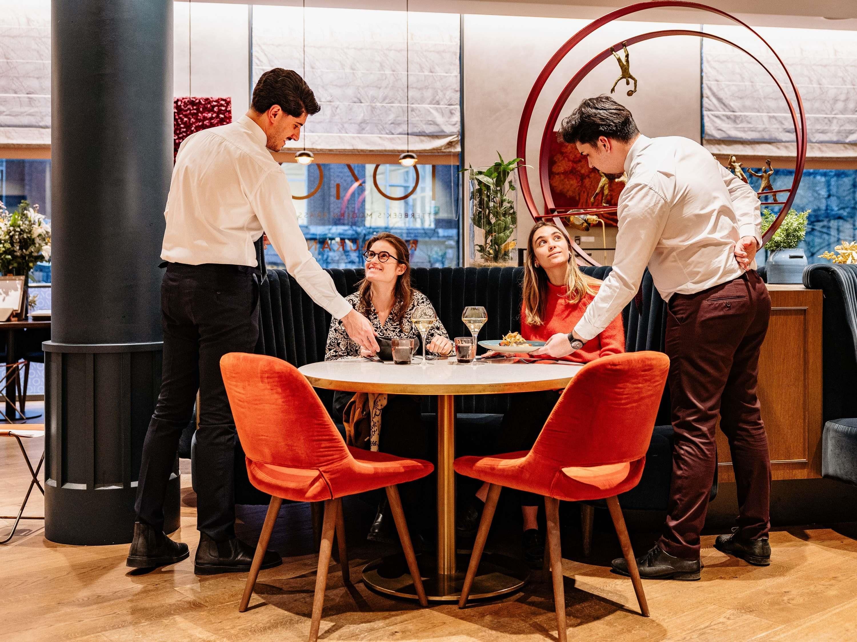 Un restaurante con una mesa redonda, sillas rojas y vistas a la ciudad.