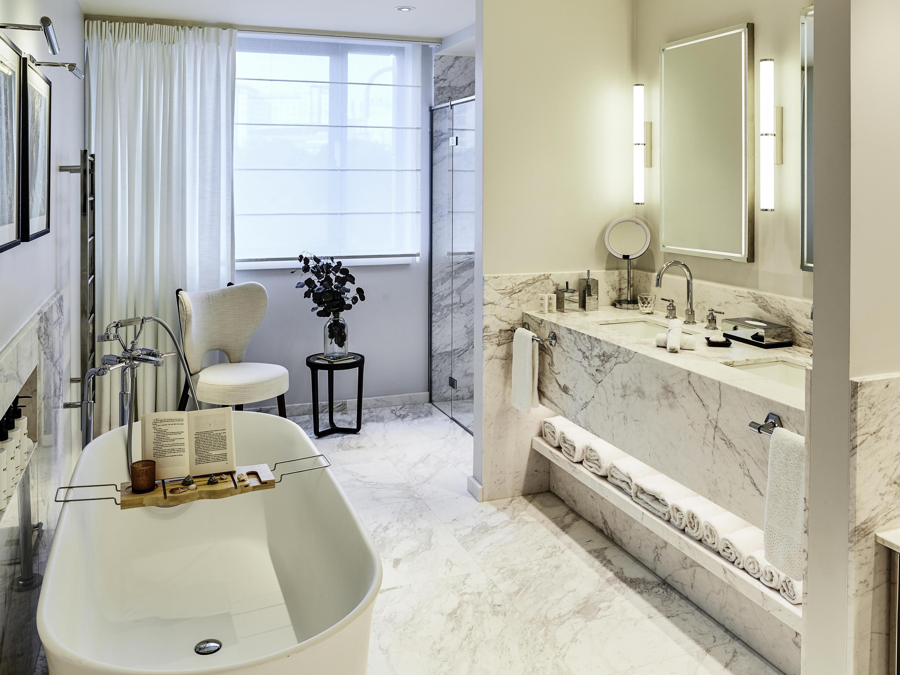 Un baño moderno con una bañera independiente, un espejo grande y una encimera de mármol.