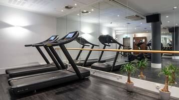 A gym with treadmills, a mirrored wall, and potted plants.