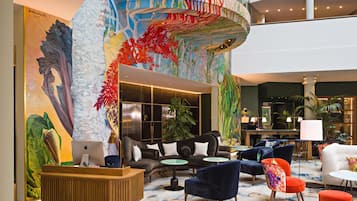 Un hall d’entrée spacieux avec un escalier central, de nombreux espaces de détente et une grande fresque murale.