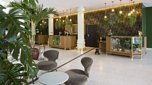 A lobby with a reception desk, seating area, and a wall with hanging plants. - Sofitel Brussels Europe (Brussels)