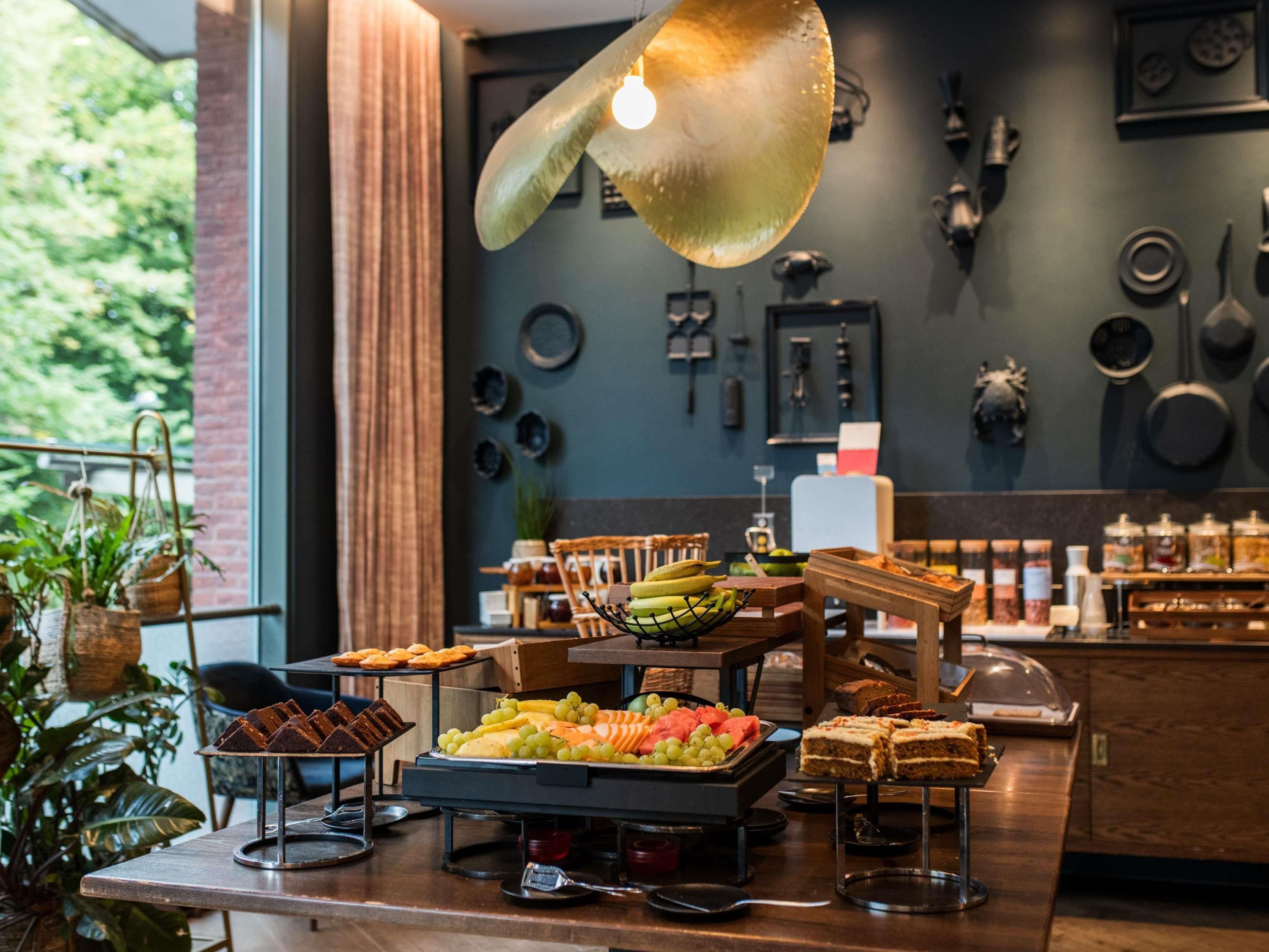 Un buffet garni de divers plats, un luminaire suspendu et des ustensiles de cuisine accrochés au mur.