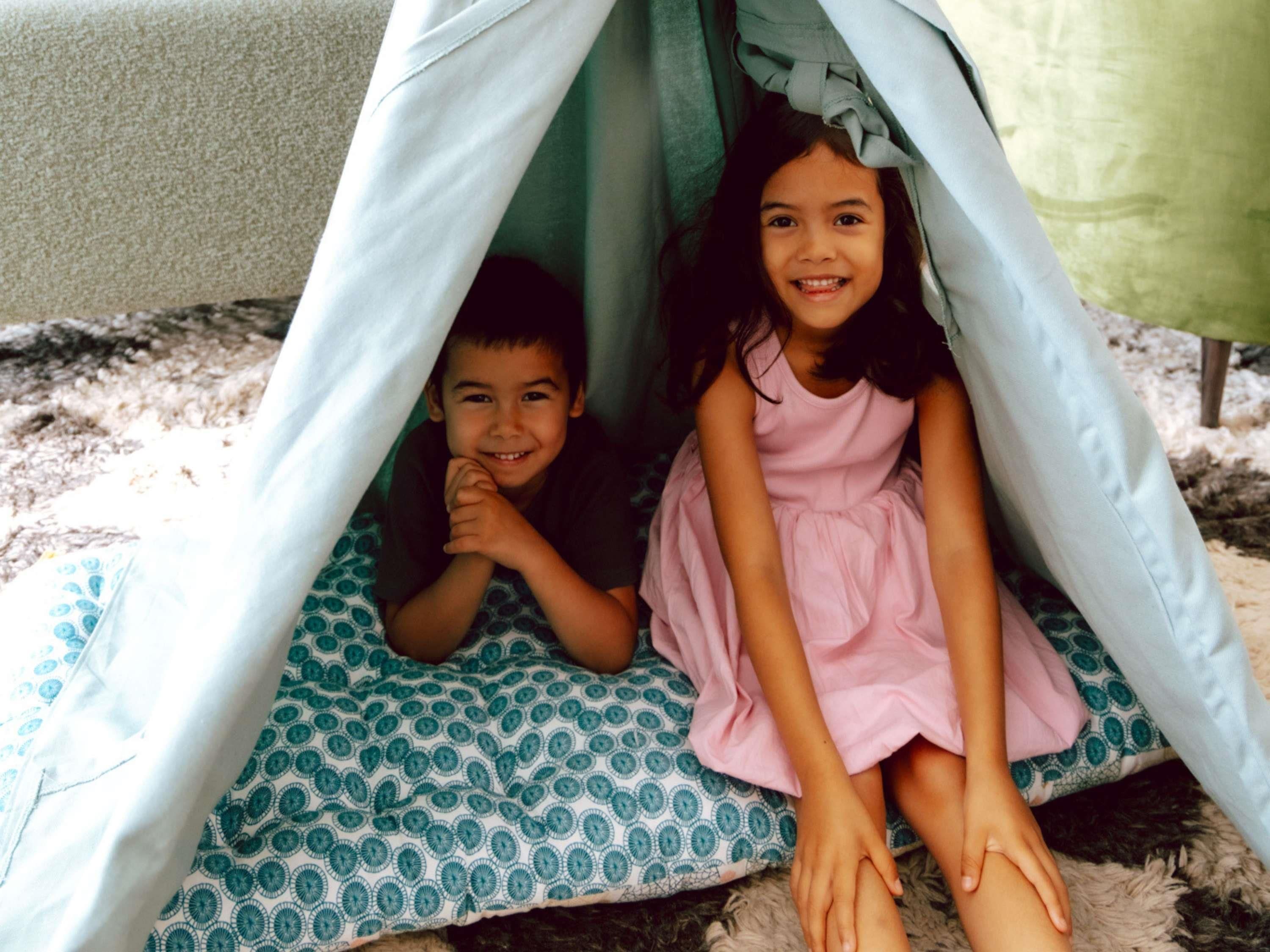 Dos niños dentro de una estructura tipo tienda con un suelo estampado.