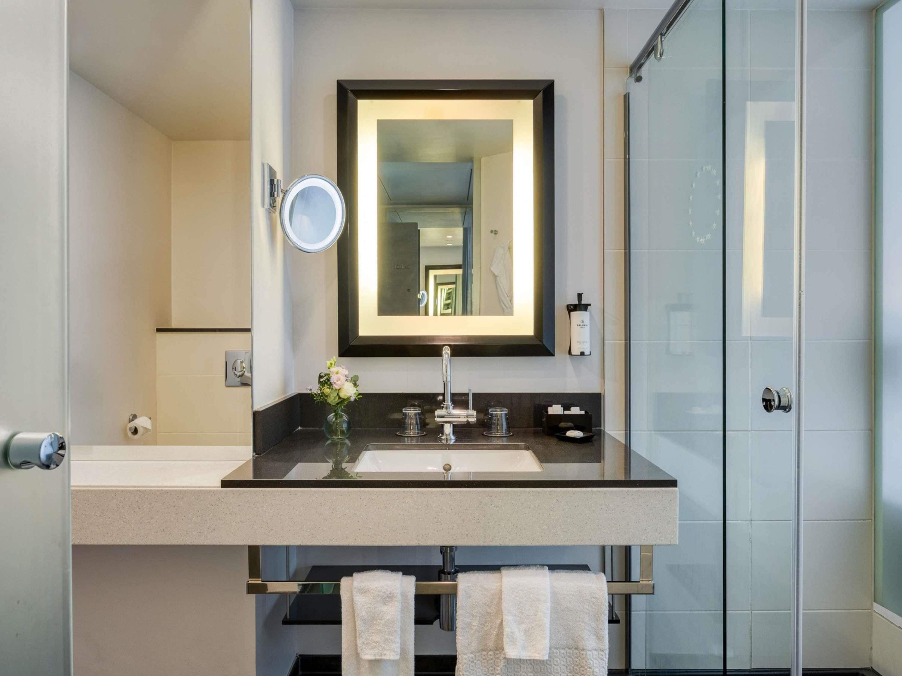 A modern bathroom with a double sink, a large mirror, and a glass shower enclosure.