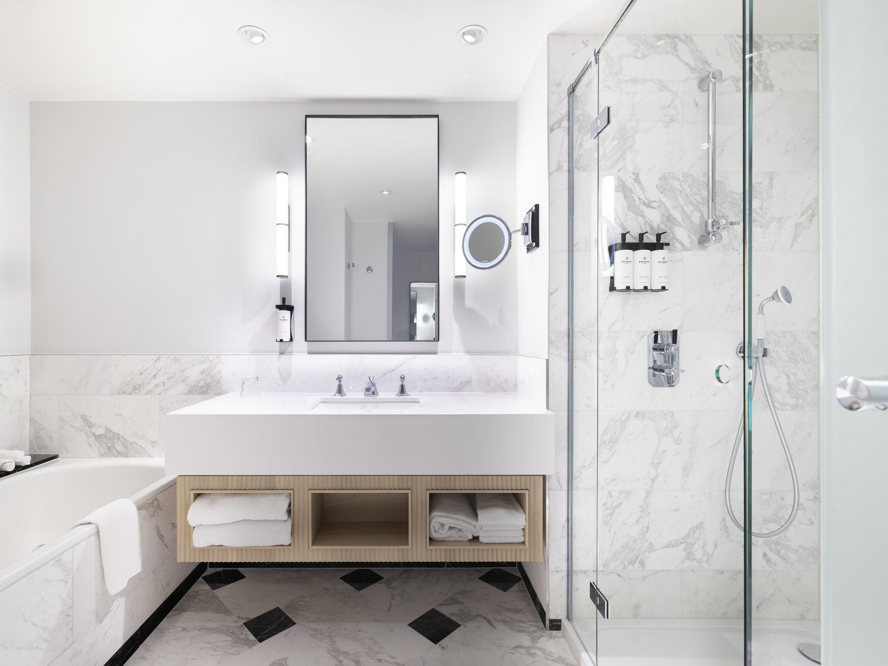 Un baño moderno con un espejo grande, una bañera, una ducha y un lavamanos.