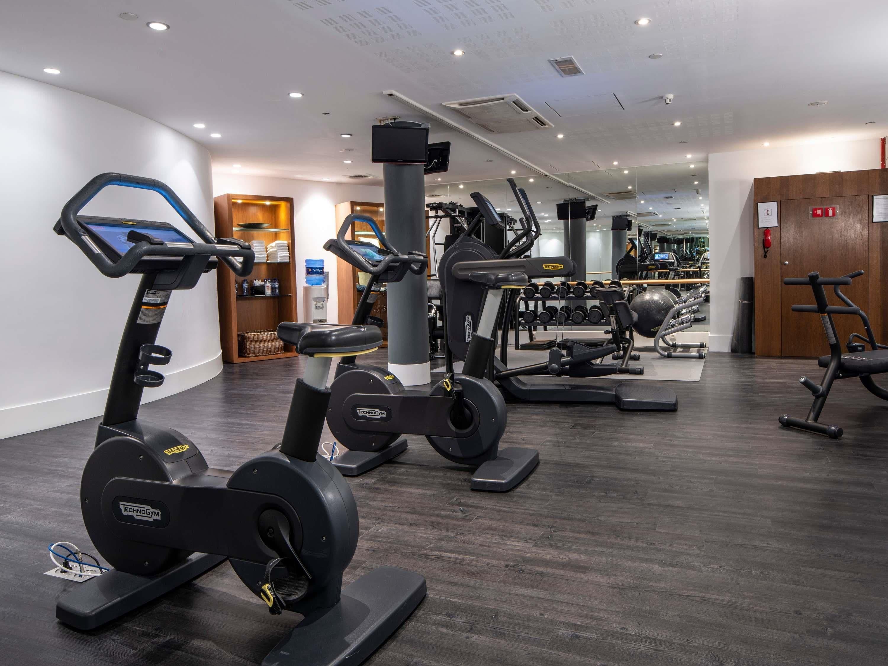 A gym with cardio machines, weightlifting equipment, and a mirror wall.