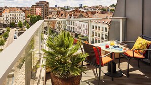 A balcony with a table, chairs, a potted plant, and a city view. - Sofitel Brussels Europe (Brussels)
