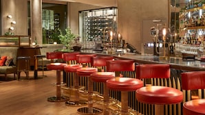 A bar area with red bar stools, a wine rack, and a bar counter. - Sofitel Brussels Europe (Brussels)
