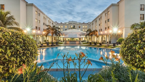 A hotel with a central pool, surrounded by palm trees and well-maintained greenery. - VIP Grand Maputo (Maputo)