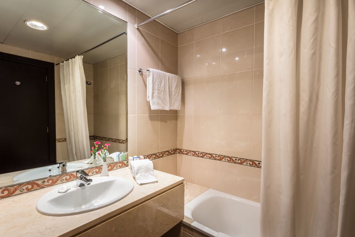 A bathroom with a sink, mirror, and bathtub.