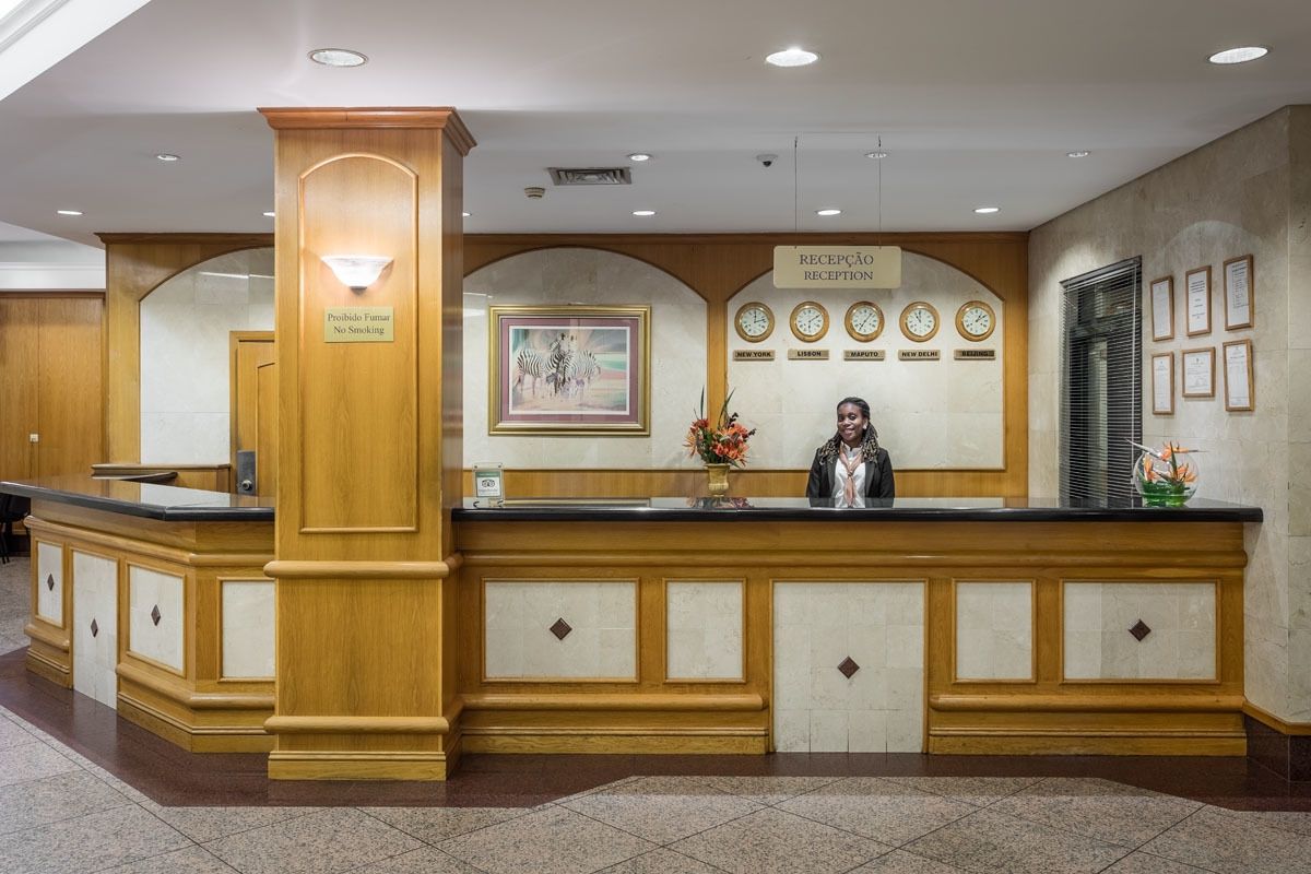 A reception desk with a "No Smoking" sign, a framed zebra painting, clocks, and framed certificates on the wall.