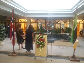 A lobby with a fountain, flags, and a podium with flowers.