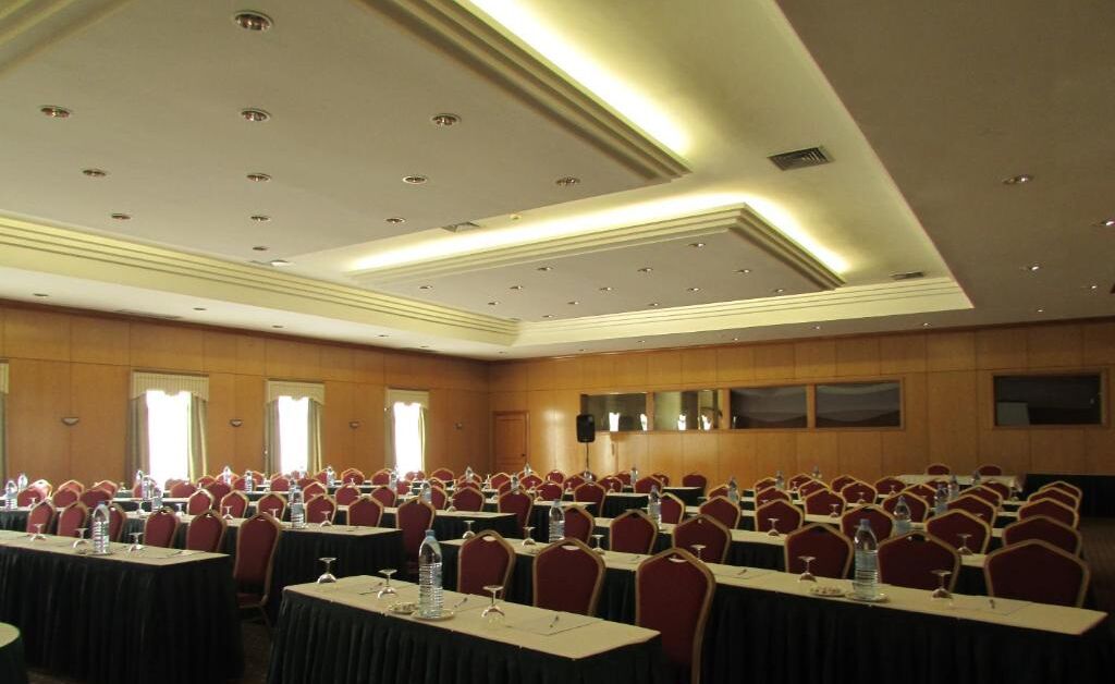 A conference room with rows of tables and chairs, equipped with water bottles and nameplates.