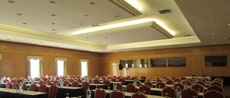 A conference room with rows of tables and chairs, equipped with water bottles and nameplates.