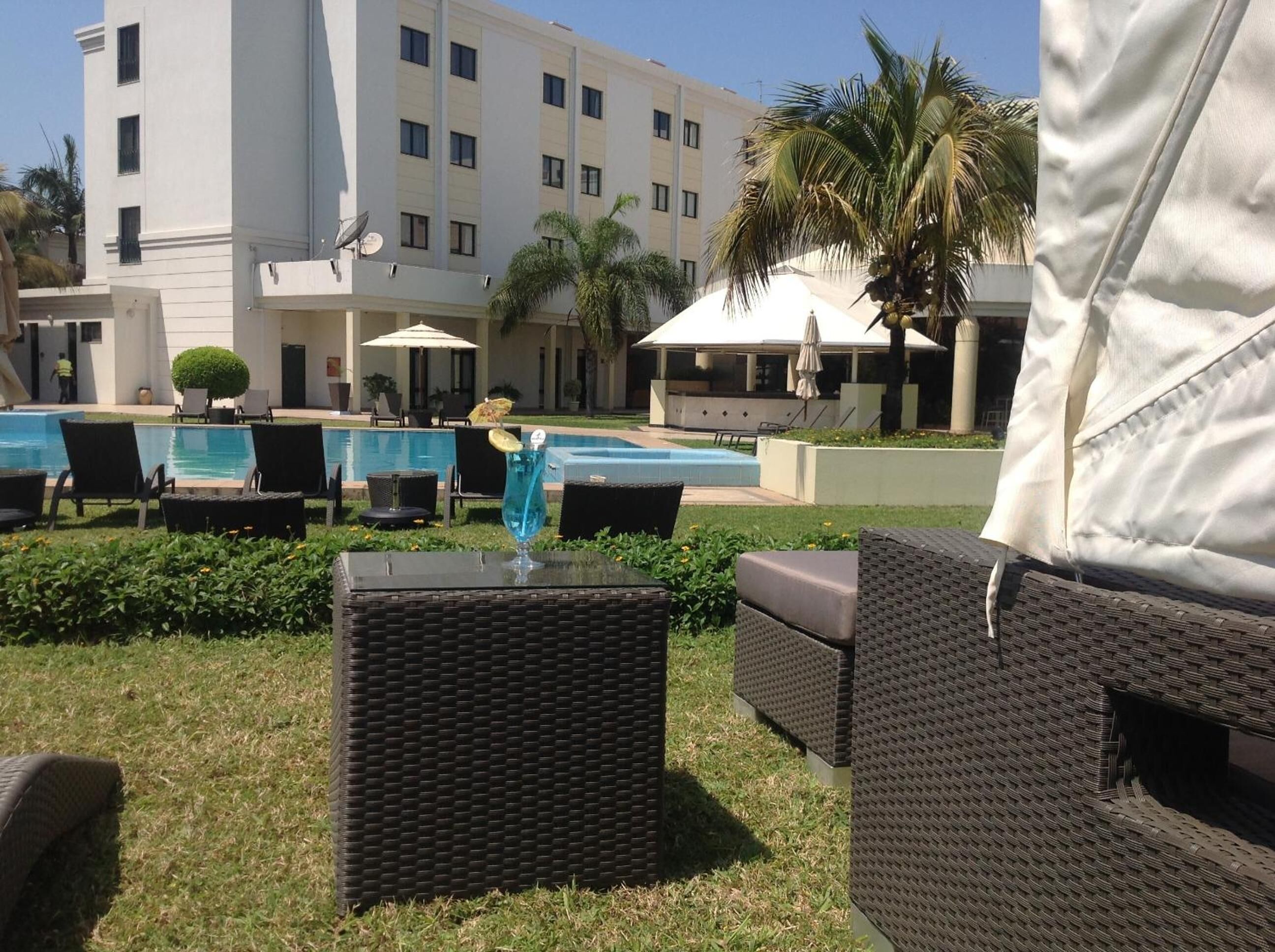 A poolside area with lounge chairs, a small table, and a building in the background.