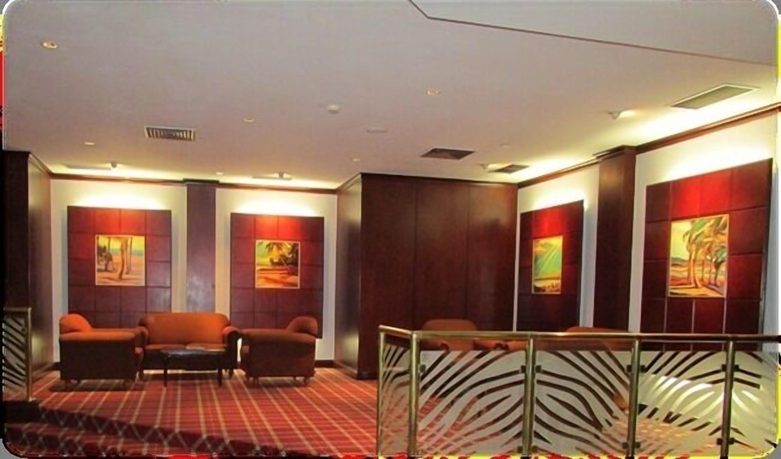 Un hall de hotel con alfombra a cuadros, dos sofás y obras de arte en las paredes.