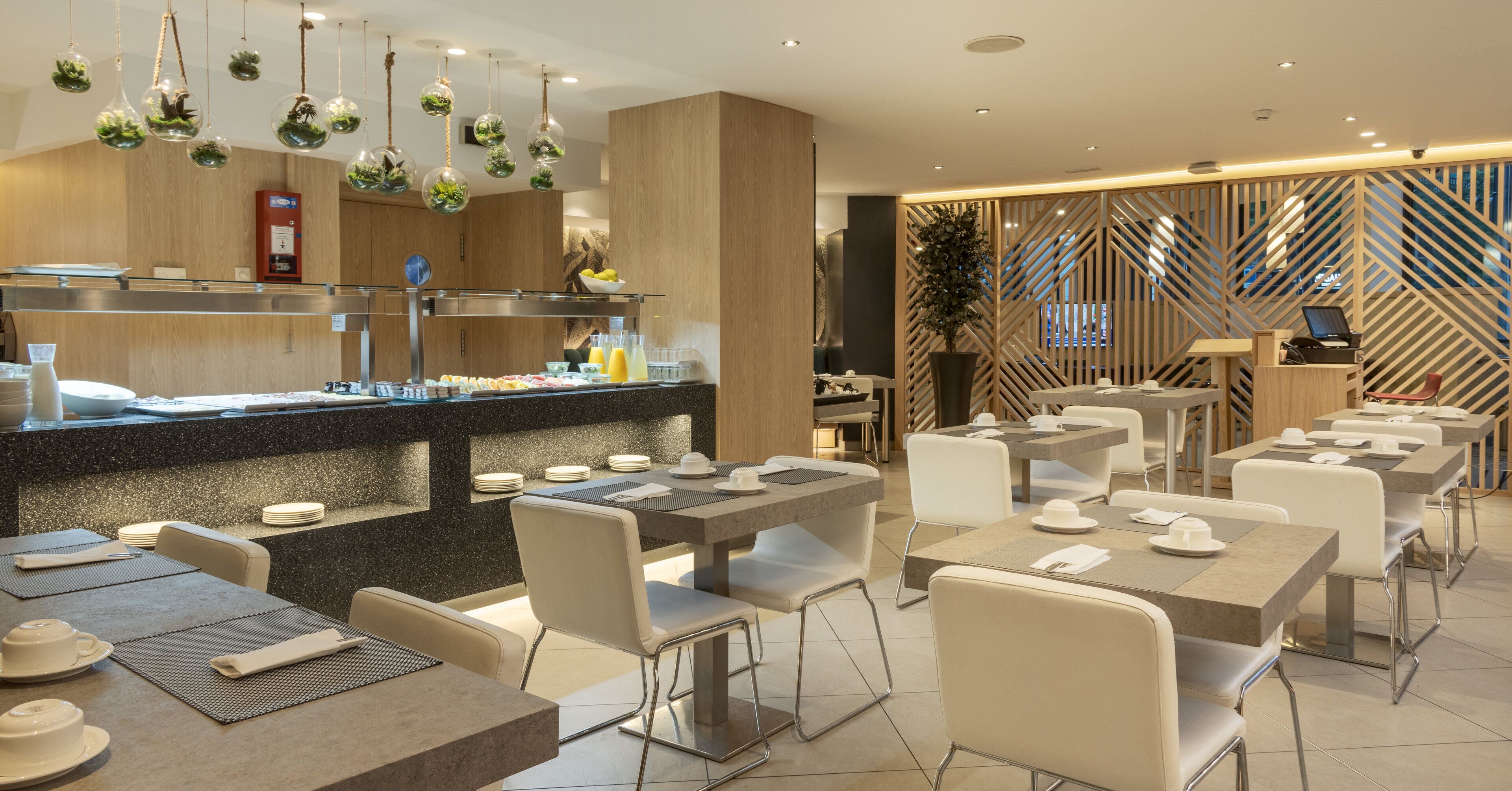 A modern restaurant with a central counter, multiple tables, and chairs.