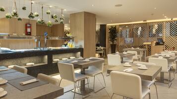 A modern restaurant with a central counter, multiple tables, and chairs.