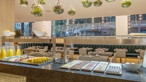 A buffet area with various food items, seating arrangements, and hanging planters. - Hotel ILUNION Auditori (Barcelona)