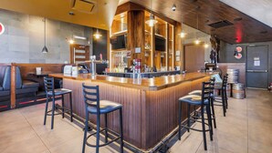 A bar area with a wooden counter, bar stools, and a seating area with a sofa and chairs. - Sandman Hotels & Suites Calgary West (Calgary)