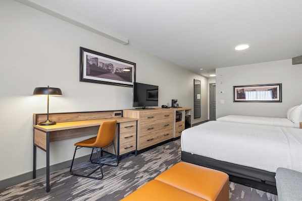 A hotel room with a bed, a desk with a chair, a television, a coffee maker, and two framed pictures on the wall. - Sandman Hotels & Suites Calgary West (Calgary)